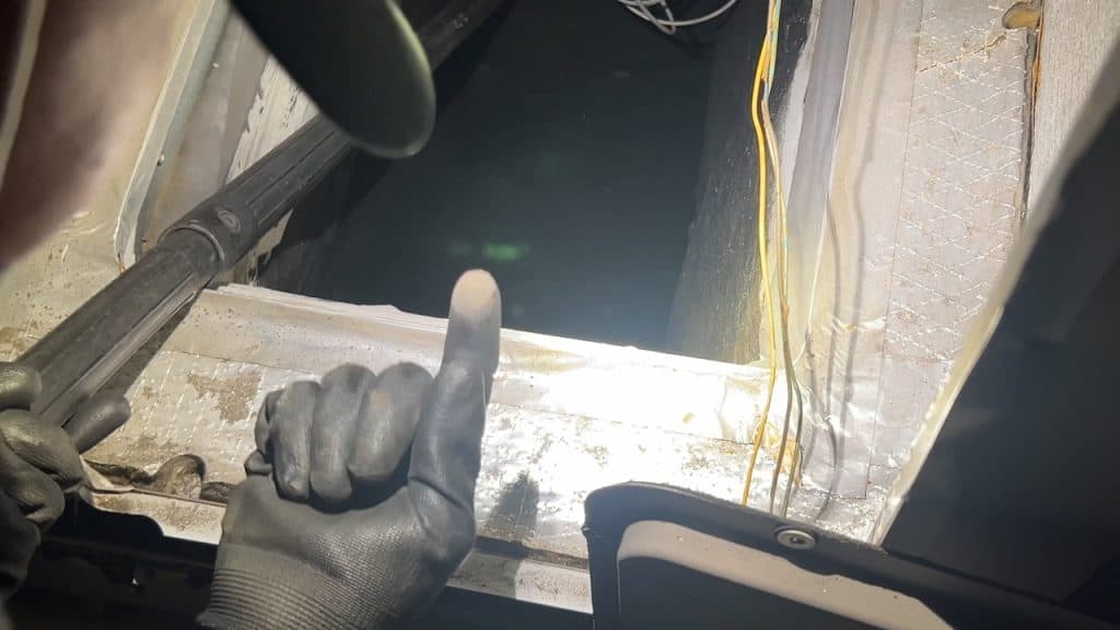 Technician inspecting grease buildup deep inside a kitchen exhaust duct